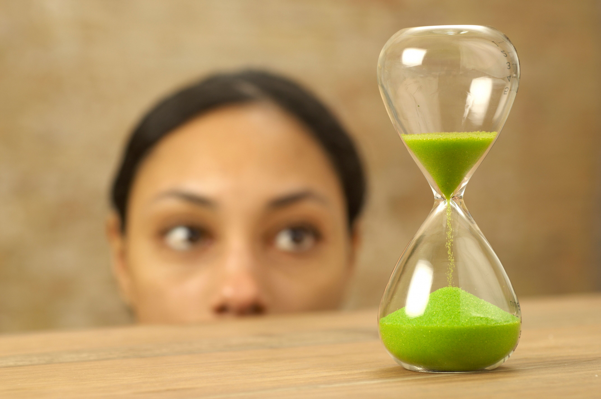 A woman looks at an hourglass as the sand runs out.